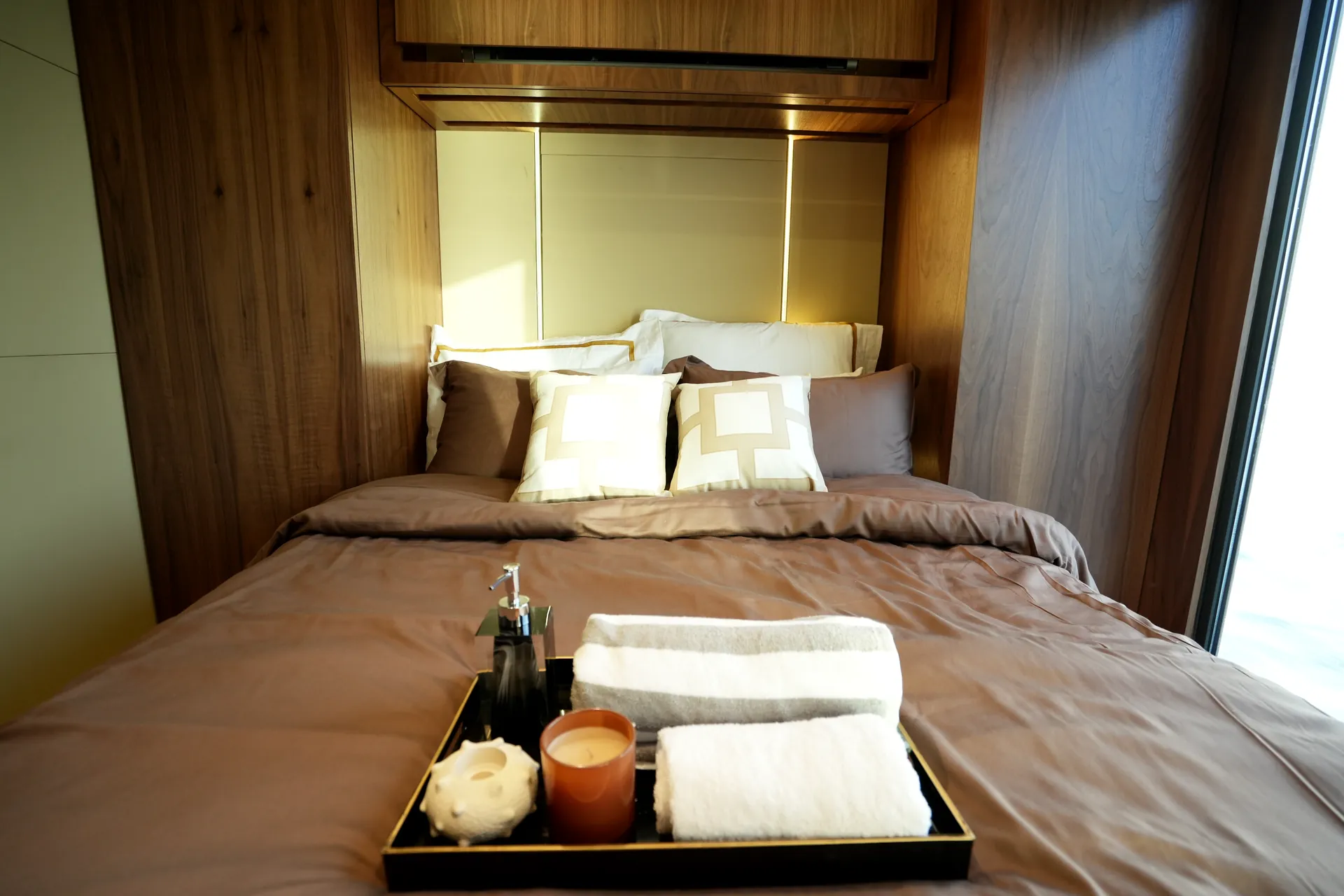 AQUATOR 40+ bedroom with a timber headboard wall and a tray of towels on the bed