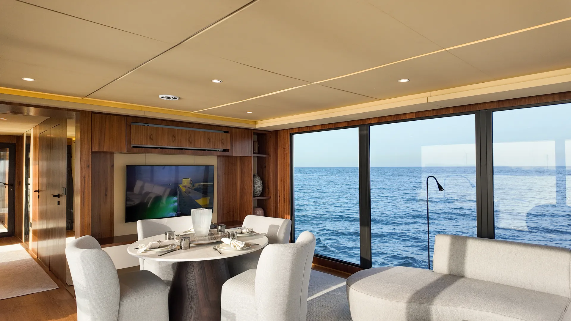 AQUATOR 50 dining table set beneath a walnut feature wall, with the sea alongside
