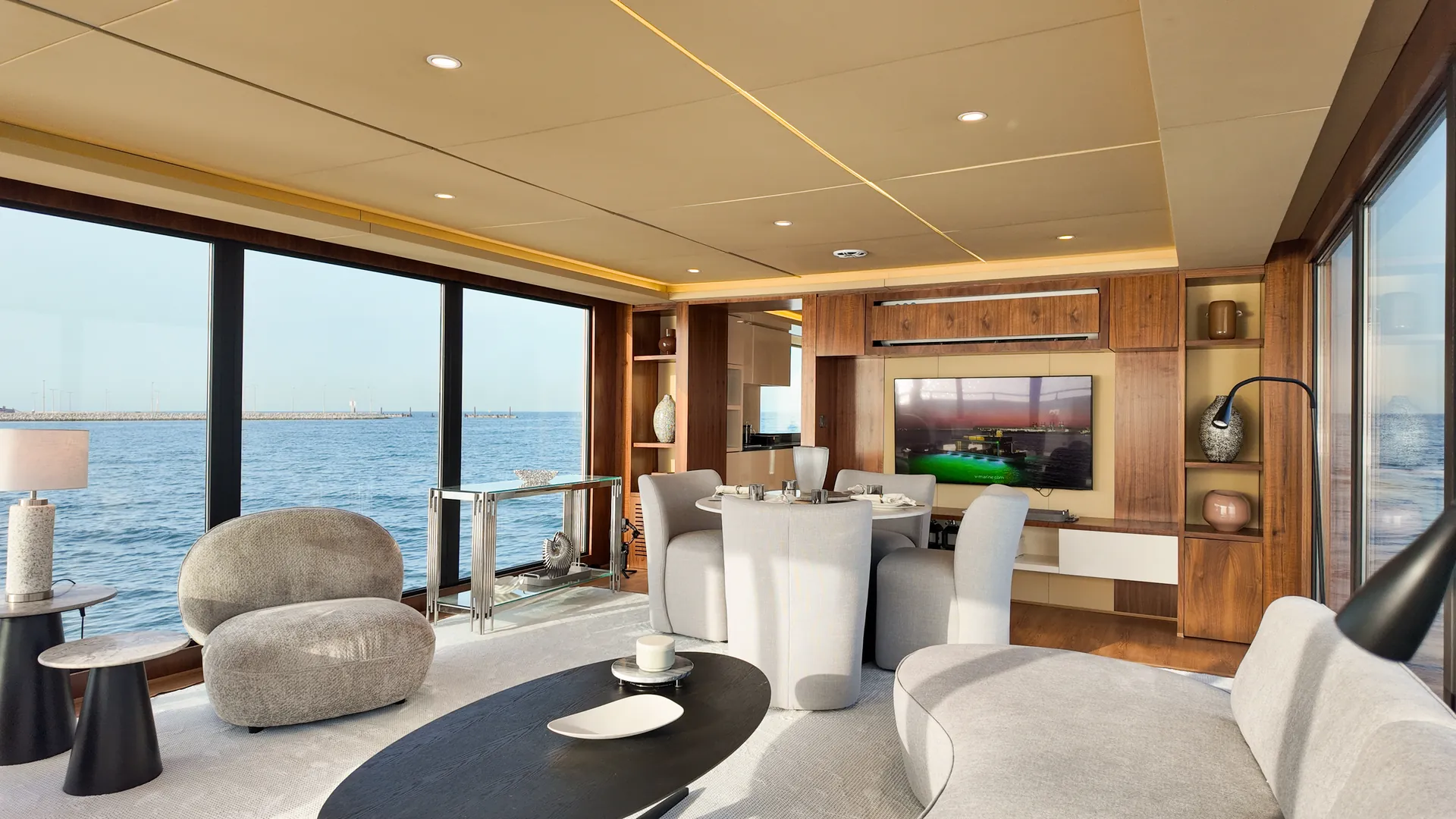 AQUATOR 50 saloon with curved sofas, an oval coffee table and the dining area beyond