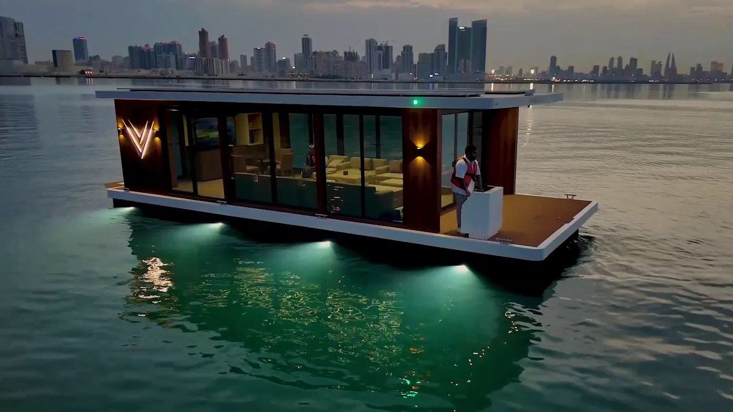 The majlis at dusk, its lounge lit through the glass and underwater lights glowing beneath