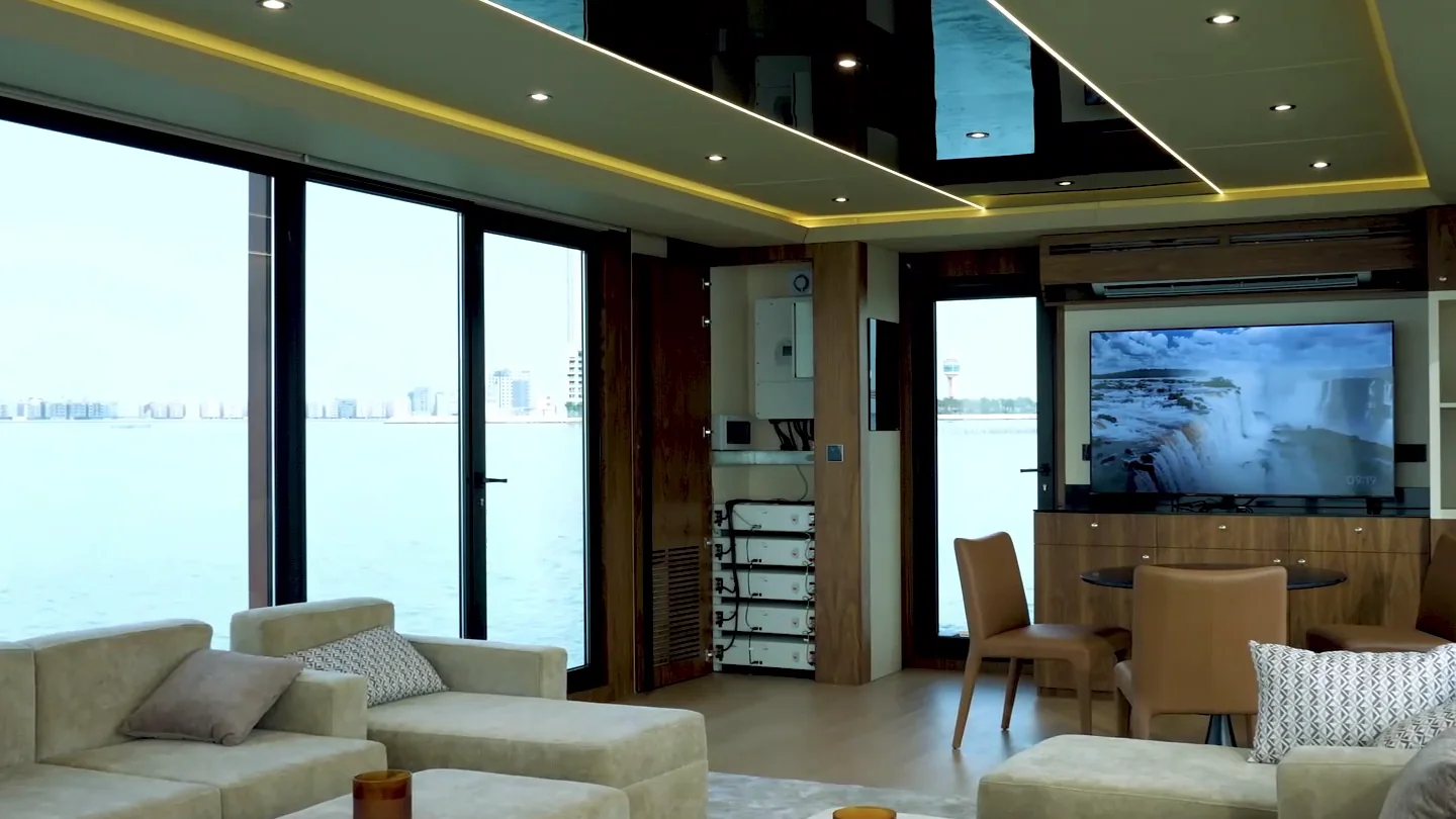 The lounge with a wall-mounted screen and a small dining table by the glass