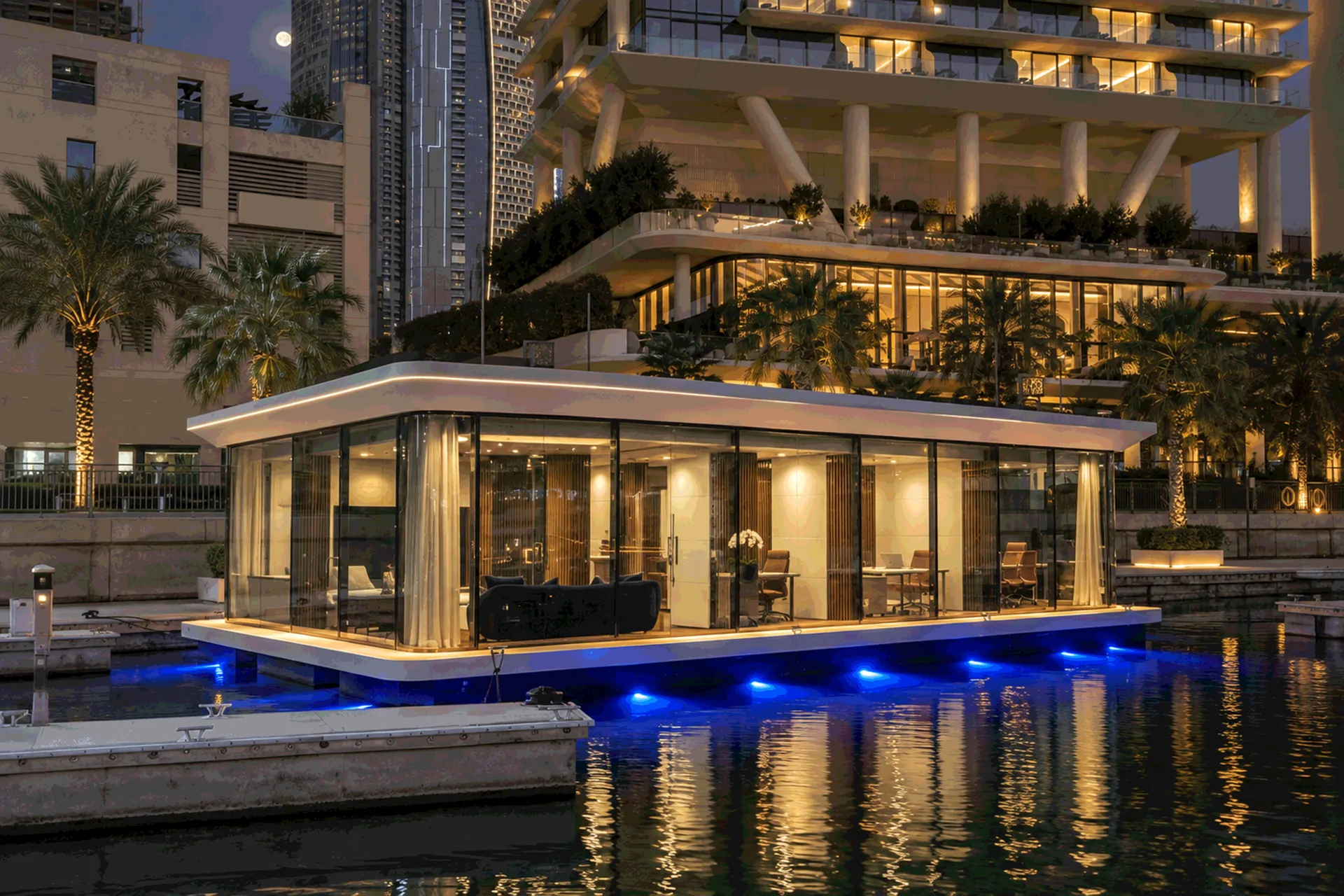 A 16 by 8 metre floating office with a curved white canopy, lit at night beside waterfront towers