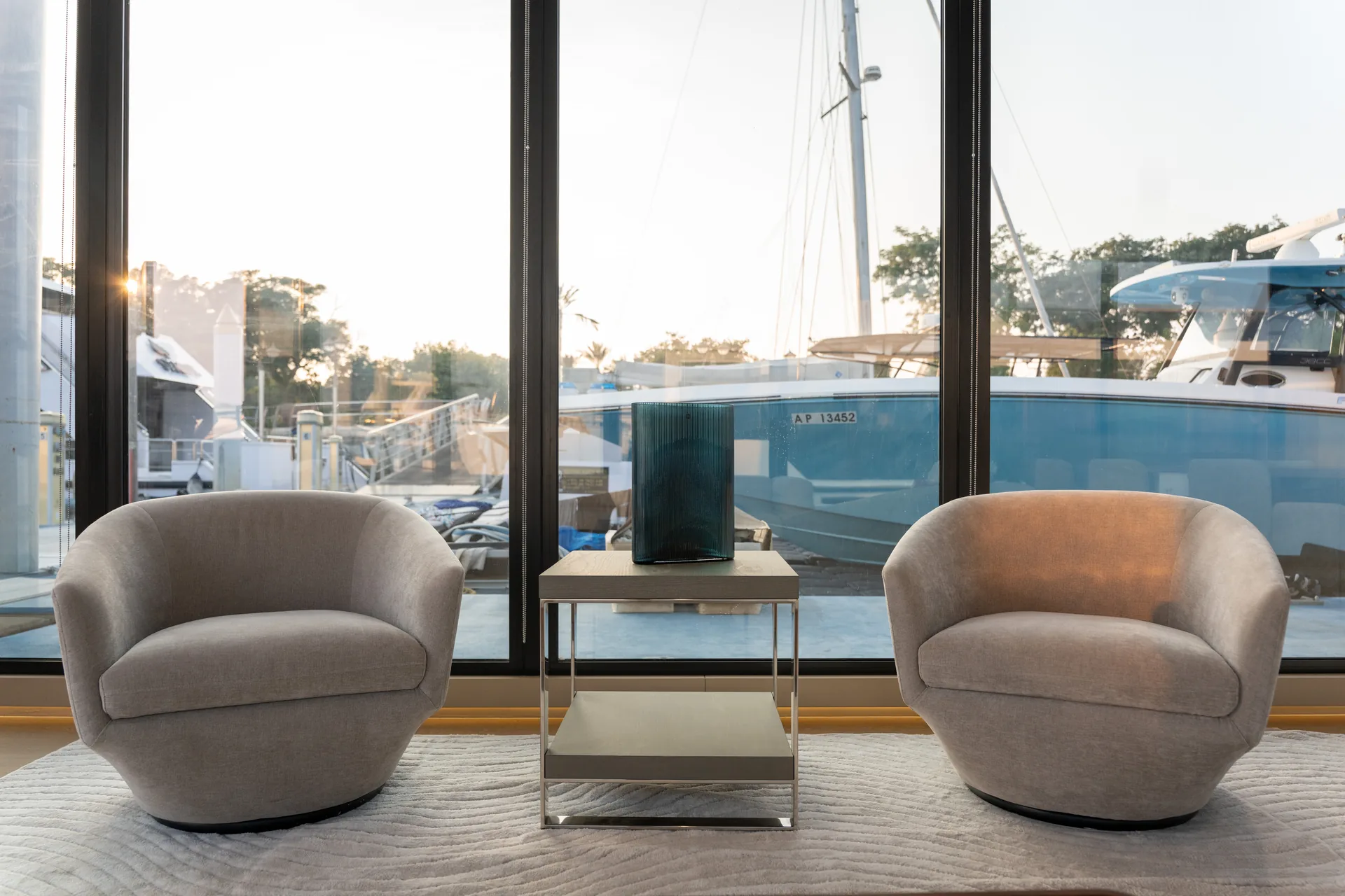 Two armchairs facing floor-to-ceiling glass and the boats in the marina