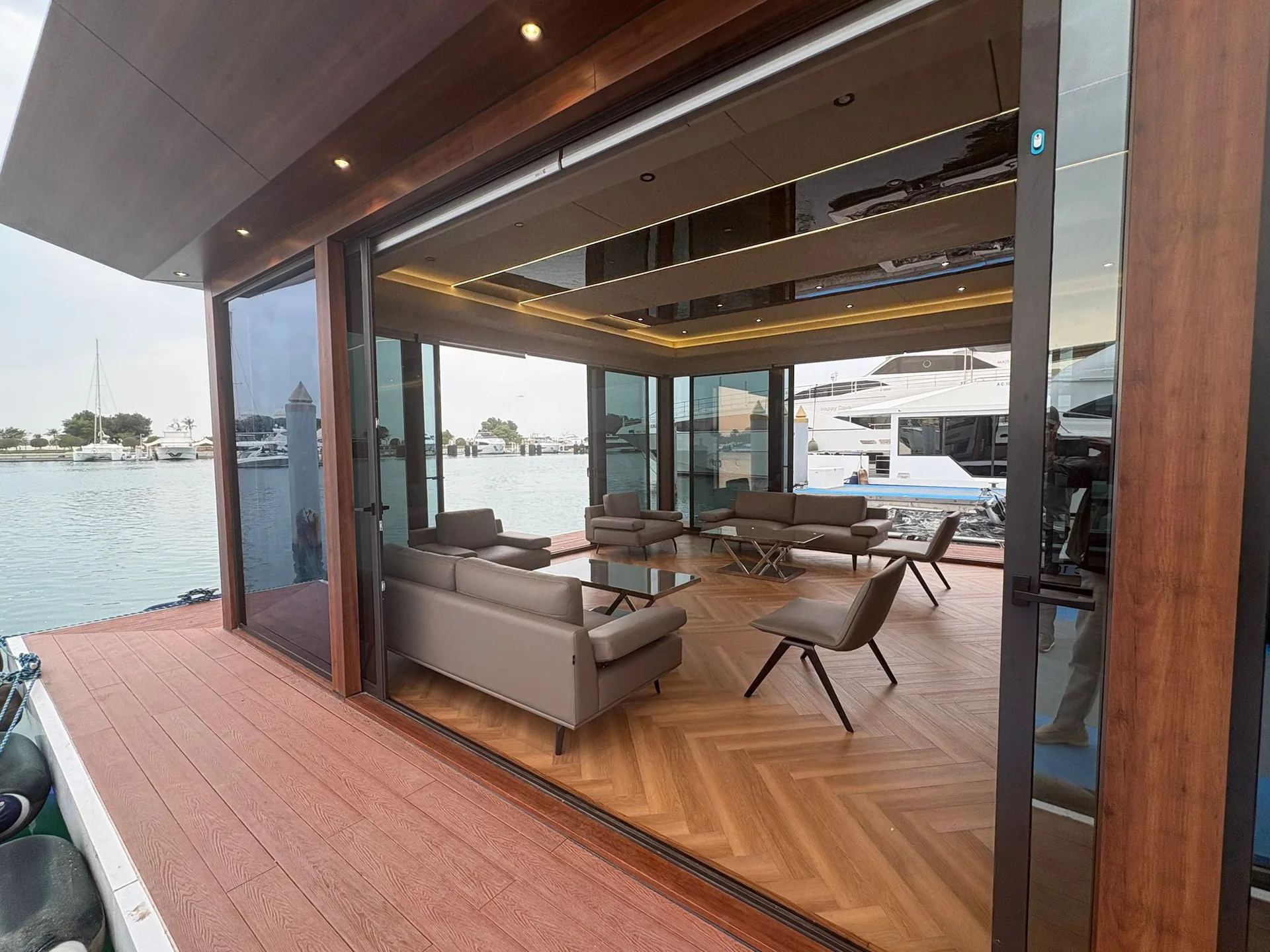 Sliding glass doors open from the deck into the lounge, with the marina beyond