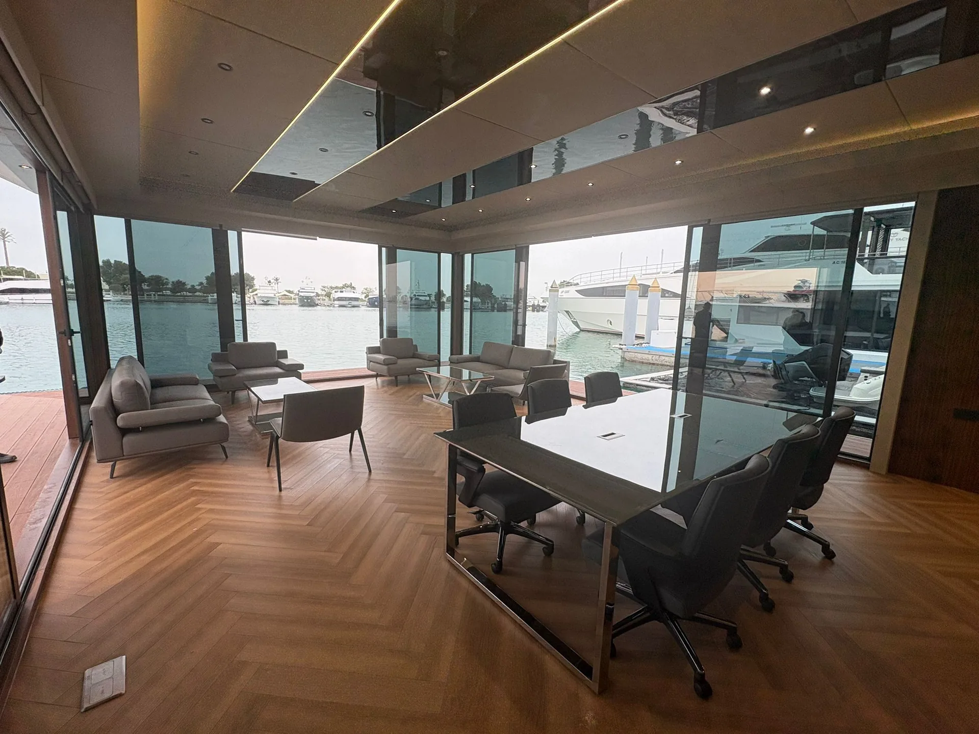 Meeting table with office chairs beside full-height windows onto the marina