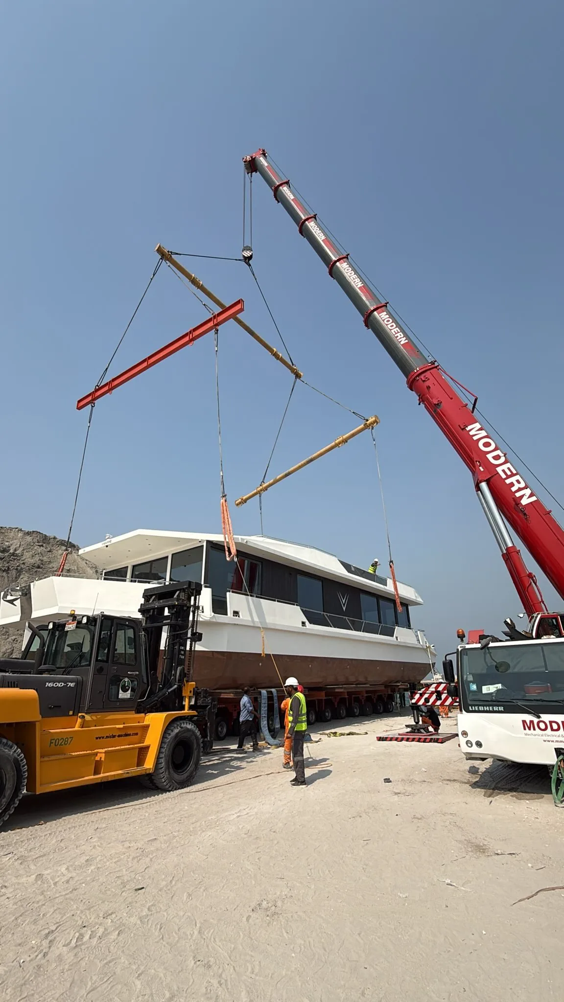 هيكل مكتمل من V-Marine على مقطورات متعددة المحاور وبجانبه رافعة متنقلة